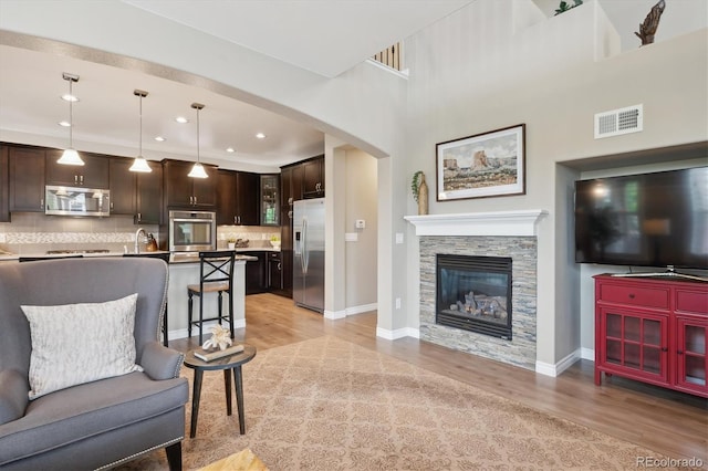 9528 Pendio Ct, Highlands Ranch, CO 80126 - living area featuring light wood-style floors, arched walkways, baseboards, recessed lighting, and a stone fireplace