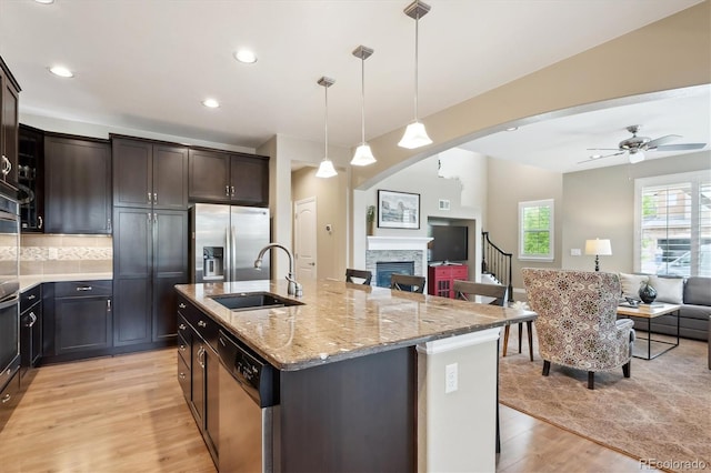 9528 Pendio Ct, Highlands Ranch, CO 80126 - kitchen with appliances with stainless steel finishes, open floor plan, a sink, light wood finished floors, and light stone countertops