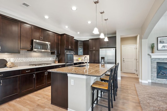 9528 Pendio Ct, Highlands Ranch, CO 80126 - kitchen with stainless steel appliances, a sink, light stone countertops, a kitchen breakfast bar, and decorative backsplash
