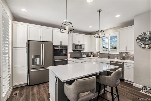 kitchen with sink, white cabinetry, hanging light fixtures, a kitchen island, and stainless steel appliances