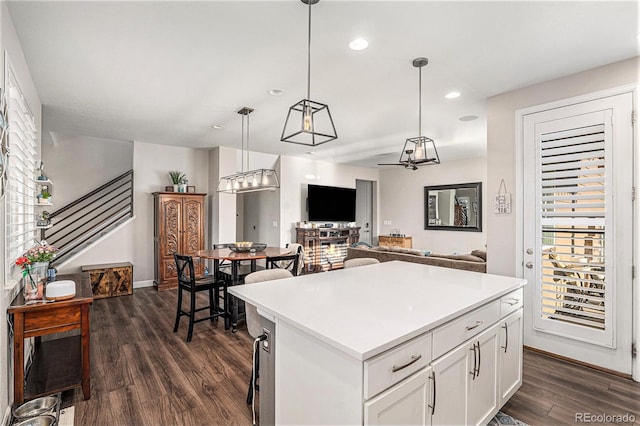 kitchen with white cabinetry, dark wood-type flooring, a kitchen island, and pendant lighting