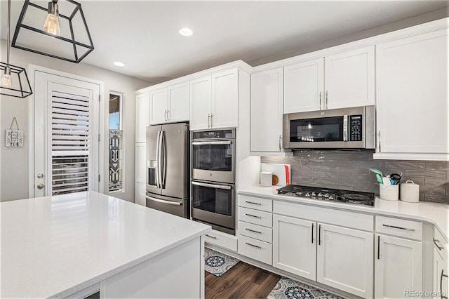 kitchen with pendant lighting, white cabinetry, stainless steel appliances, and backsplash