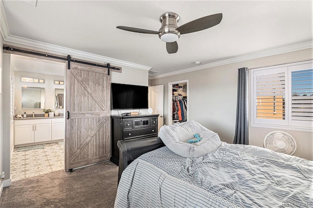 carpeted bedroom with ensuite bathroom, crown molding, a walk in closet, a closet, and a barn door