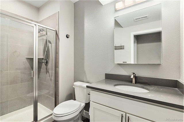 bathroom with vanity, a shower with shower door, and toilet