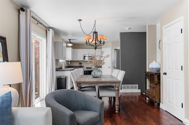 8864 S Field Ct, Littleton, CO 80128 - dining space with a chandelier, dark wood-style flooring, and baseboards