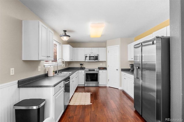 8864 S Field Ct, Littleton, CO 80128 - kitchen featuring appliances with stainless steel finishes, a sink, dark countertops, dark wood-style flooring, and white cabinetry