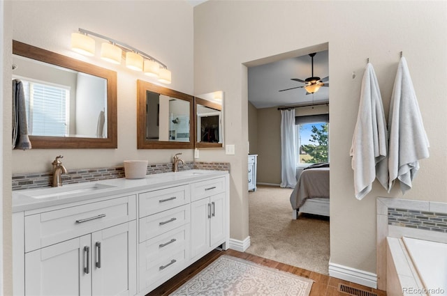 8864 S Field Ct, Littleton, CO 80128 - full bathroom with double vanity, wood finished floors, tiled bath, ceiling fan, and baseboards