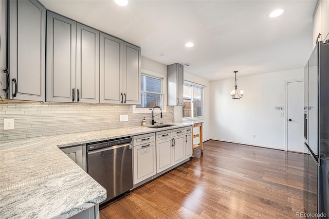 kitchen with gray cabinetry, light stone counters, sink, and stainless steel dishwasher