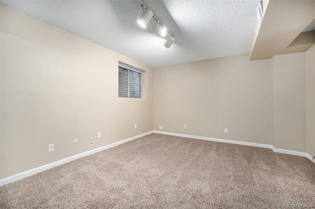 basement with carpet flooring, rail lighting, and a textured ceiling