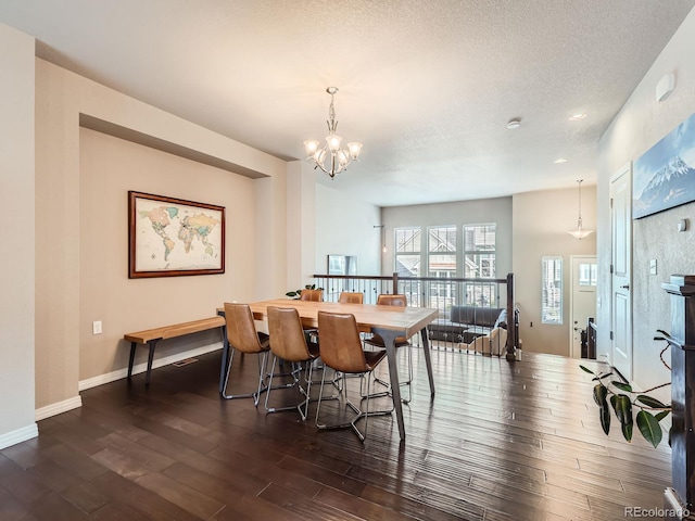 dining room with dark hardwood / wood-style floors, a textured ceiling, and an inviting chandelier