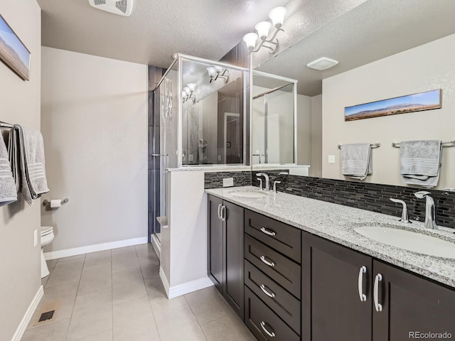 bathroom with vanity, tile patterned floors, a textured ceiling, walk in shower, and tasteful backsplash