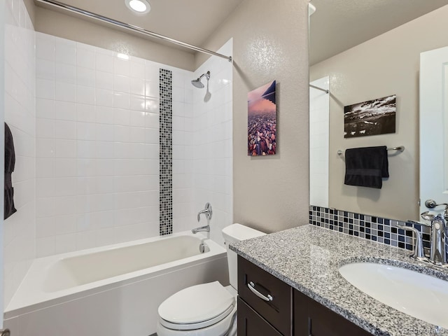 full bathroom featuring vanity, tiled shower / bath combo, and toilet