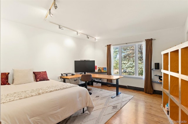 bedroom with hardwood / wood-style floors and track lighting