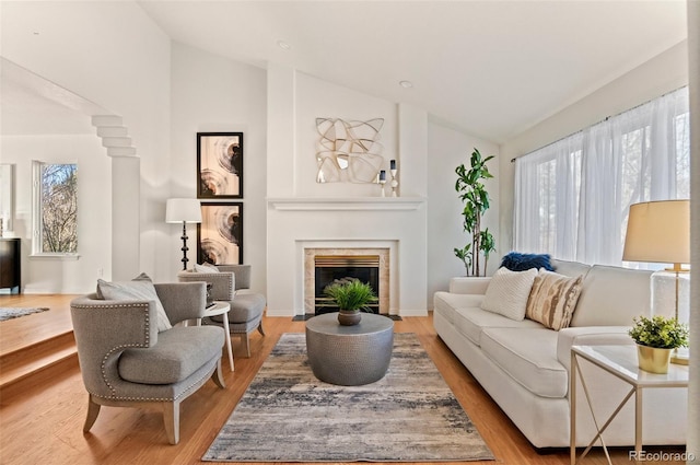 living room with a tile fireplace, light hardwood / wood-style flooring, and vaulted ceiling