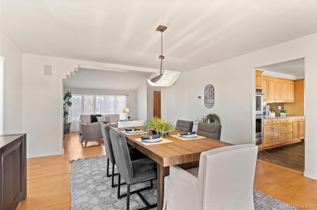 dining space with light hardwood / wood-style flooring and lofted ceiling