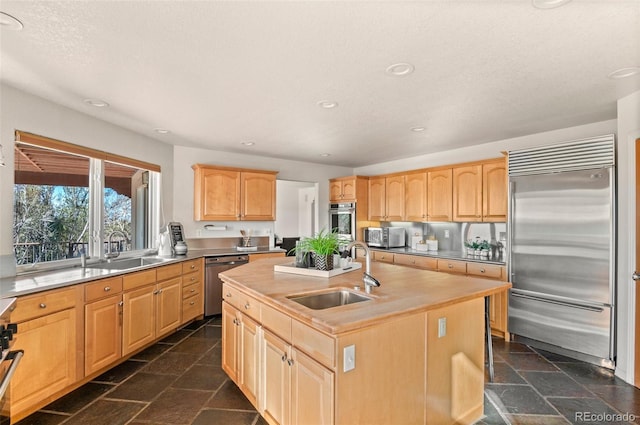 kitchen featuring sink, a center island with sink, light brown cabinets, and appliances with stainless steel finishes