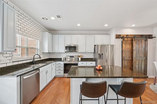 18173 E Saskatoon Pl, Parker, CO 80134 - kitchen with appliances with stainless steel finishes, a breakfast bar, decorative backsplash, white cabinets, and recessed lighting