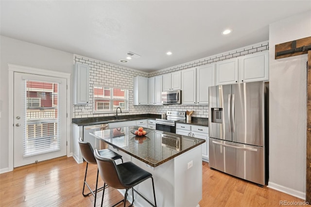 18173 E Saskatoon Pl, Parker, CO 80134 - kitchen featuring appliances with stainless steel finishes, a breakfast bar area, light wood-style floors, tasteful backsplash, and recessed lighting