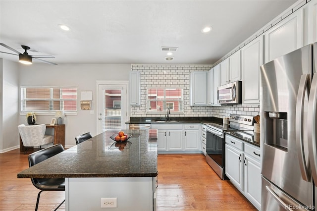 18173 E Saskatoon Pl, Parker, CO 80134 - kitchen with stainless steel appliances, a kitchen breakfast bar, a ceiling fan, a kitchen island, and light wood finished floors