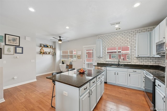 18173 E Saskatoon Pl, Parker, CO 80134 - kitchen featuring stainless steel appliances, a center island, a kitchen bar, ceiling fan, and white cabinets