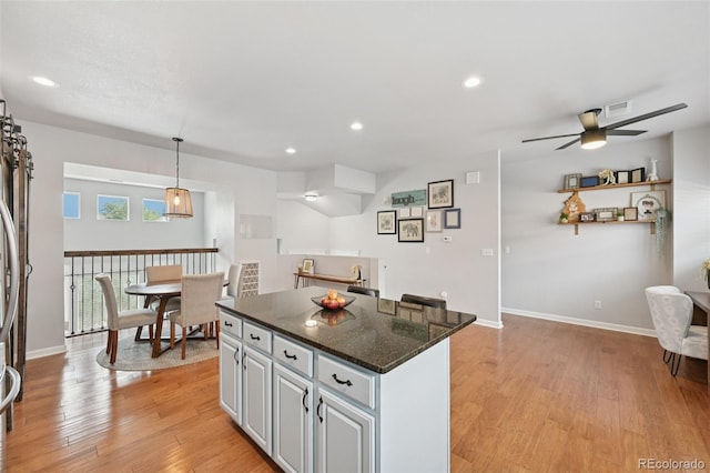 18173 E Saskatoon Pl, Parker, CO 80134 - kitchen featuring a kitchen island, a ceiling fan, light wood-style flooring, recessed lighting, and dark stone counters