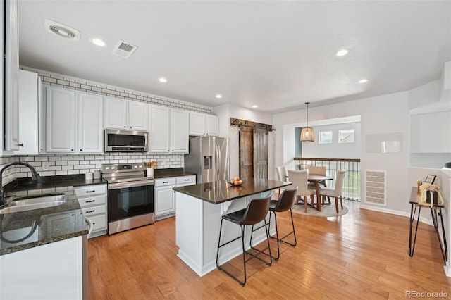 18173 E Saskatoon Pl, Parker, CO 80134 - kitchen featuring stainless steel appliances, a breakfast bar, tasteful backsplash, white cabinetry, and a center island