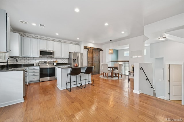 18173 E Saskatoon Pl, Parker, CO 80134 - kitchen with appliances with stainless steel finishes, a center island, tasteful backsplash, dark countertops, and a breakfast bar area