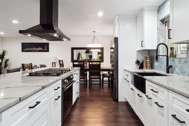 kitchen with island range hood, white cabinets, dark wood-style floors, light stone countertops, and a sink