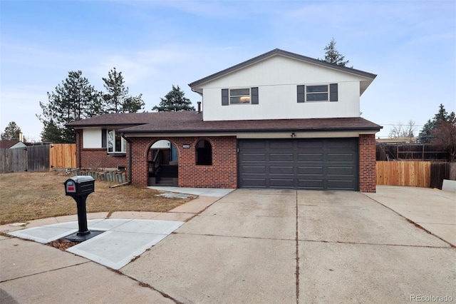 tri-level home with concrete driveway, brick siding, an attached garage, and fence