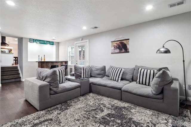 living area with a textured ceiling, dark wood-style flooring, visible vents, and recessed lighting