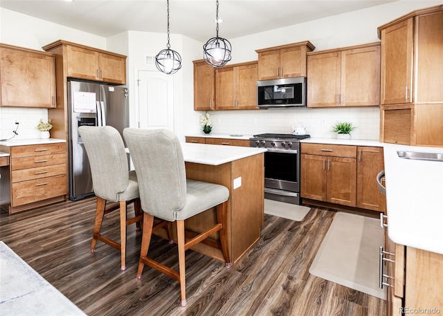 4330 Prairie Agate Dr, Colorado Springs, CO 80938 - kitchen with appliances with stainless steel finishes, dark wood-style floors, a kitchen island, a breakfast bar, and decorative backsplash