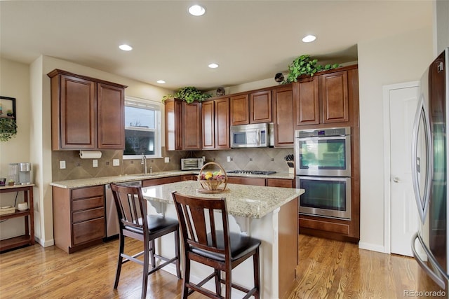 2033 E 167th Way, Thornton, CO 80602 - kitchen with stainless steel appliances, light wood-type flooring, a center island, a breakfast bar, and recessed lighting