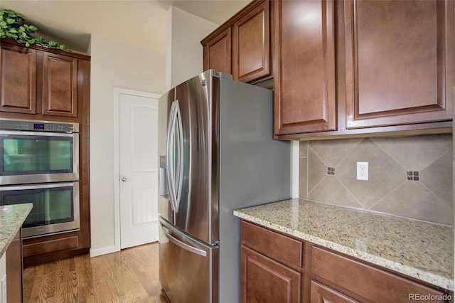 2033 E 167th Way, Thornton, CO 80602 - kitchen featuring stainless steel appliances, tasteful backsplash, light wood-type flooring, and light stone counters