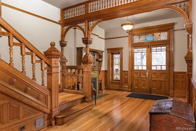 131 N Sherman St, Denver, CO 80203 - foyer entrance featuring a wainscoted wall, stairs, light wood-style flooring, and arched walkways