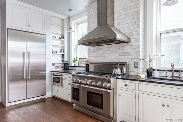 131 N Sherman St, Denver, CO 80203 - kitchen with high quality appliances, wall chimney range hood, dark countertops, open shelves, and tasteful backsplash