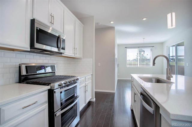 kitchen with pendant lighting, stainless steel appliances, sink, and white cabinets