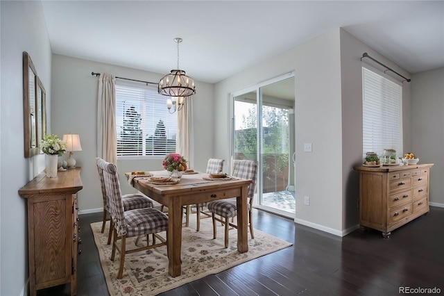 dining space with dark hardwood / wood-style flooring and a notable chandelier