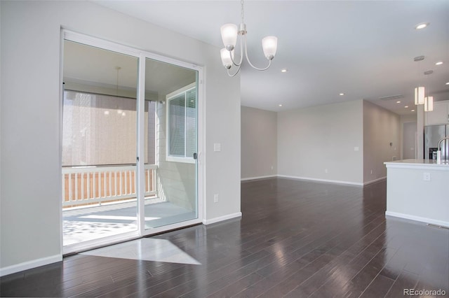 unfurnished room with plenty of natural light, dark hardwood / wood-style floors, and an inviting chandelier