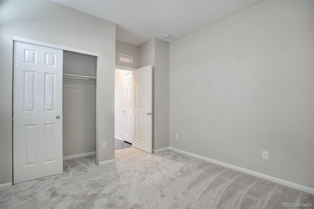 unfurnished bedroom featuring light carpet and a closet