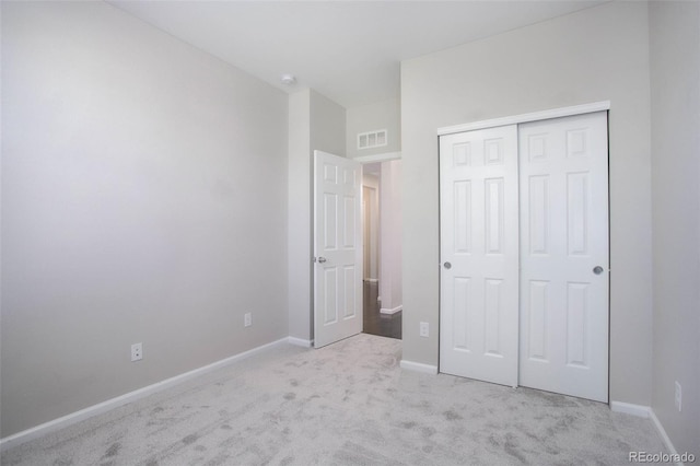 unfurnished bedroom with light colored carpet and a closet