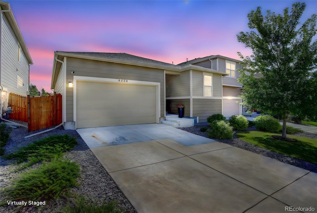 view of front of home featuring a garage, concrete driveway, and fence