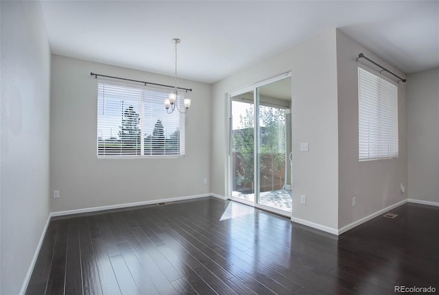 empty room with an inviting chandelier, dark wood-style floors, baseboards, and visible vents