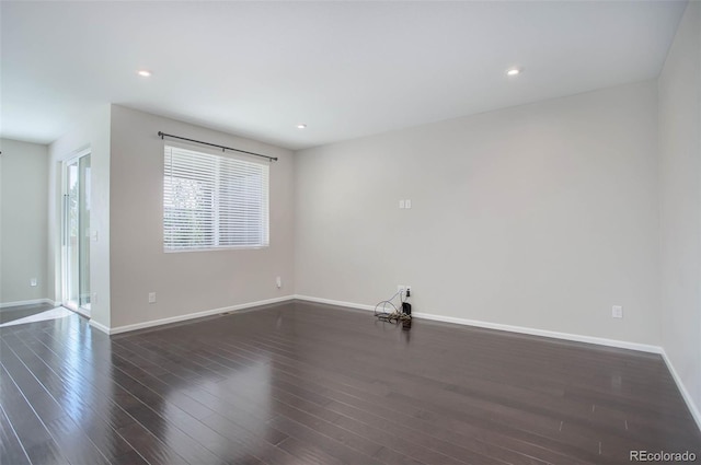 empty room featuring recessed lighting, baseboards, and dark wood-type flooring