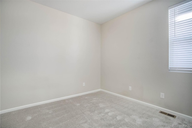 empty room featuring visible vents, baseboards, and carpet