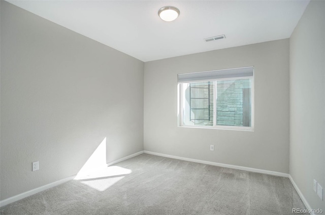 carpeted spare room featuring visible vents and baseboards