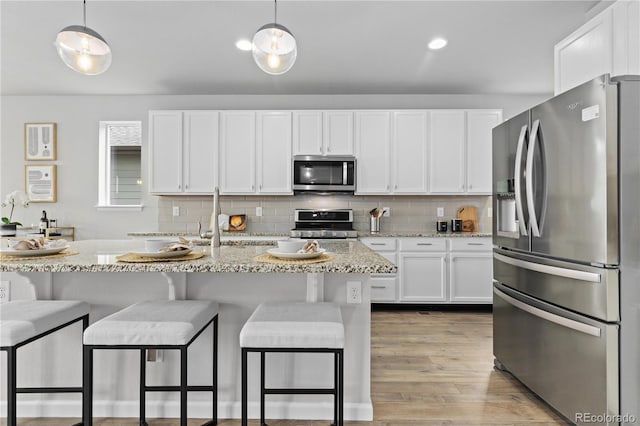 18815 W 93rd Ave, Arvada, CO 80007 - kitchen with appliances with stainless steel finishes, white cabinetry, backsplash, and light stone counters