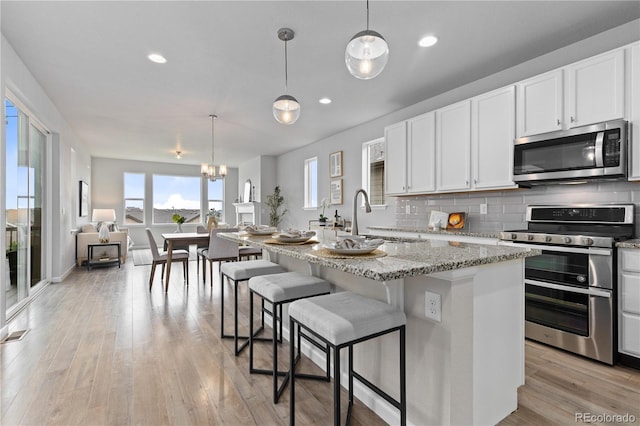18815 W 93rd Ave, Arvada, CO 80007 - kitchen featuring stainless steel appliances, light stone counters, decorative backsplash, white cabinets, and recessed lighting
