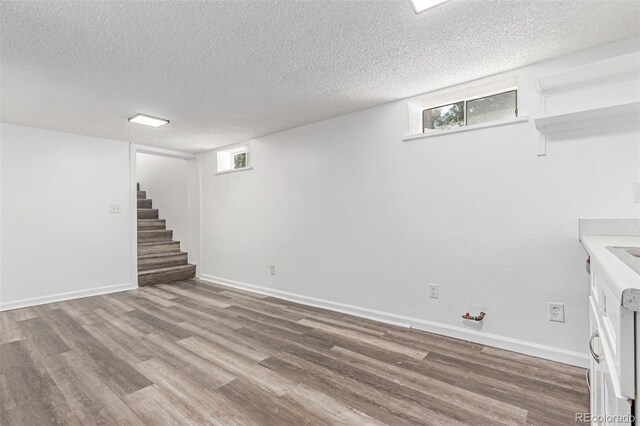4450 S Fox St, Englewood, CO 80110 - basement featuring wood finished floors, stairs, a textured ceiling, and healthy amount of natural light