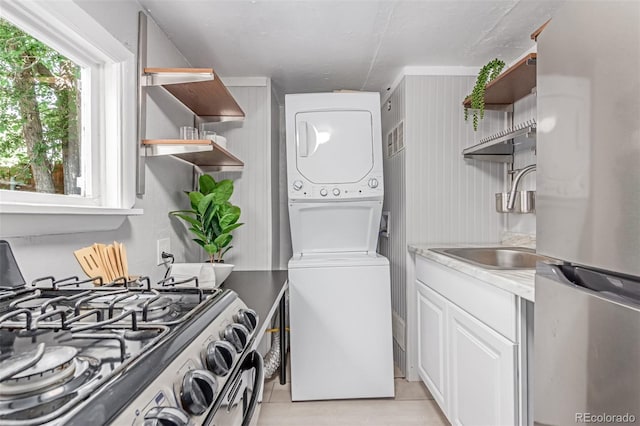 4450 S Fox St, Englewood, CO 80110 - laundry area featuring stacked washer / drying machine and light tile patterned flooring