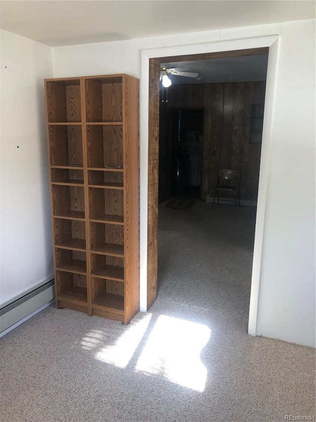 empty room featuring carpet floors, ceiling fan, and baseboard heating